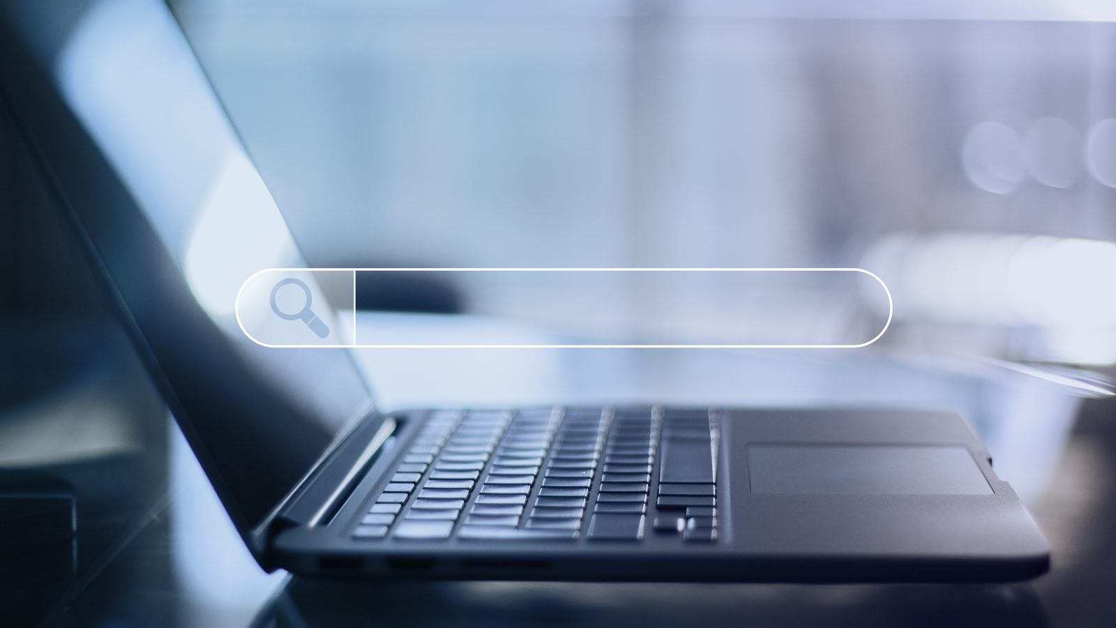A laptop on a desk with a glowing search bar graphic floating above the keyboard.