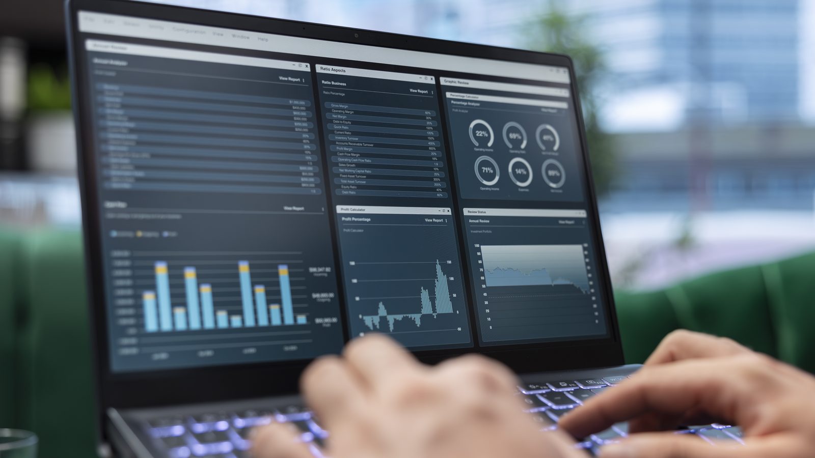 Hands type on a laptop showing a dashboard of bar charts, line graphs and gauges.