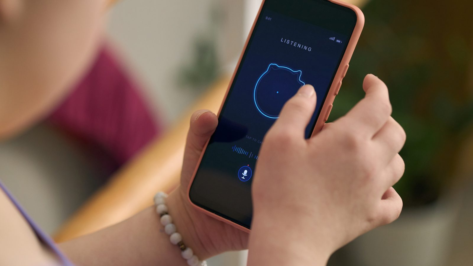 A young girl holds a phone showing a voice app that is listening.
