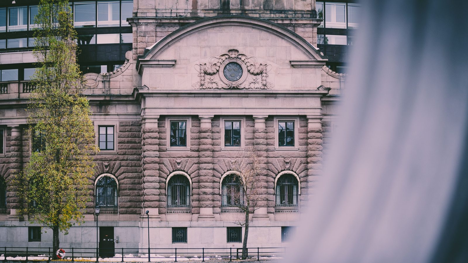 The stone facade of the Parliament House in Stockholm, seen past a blurred foreground.